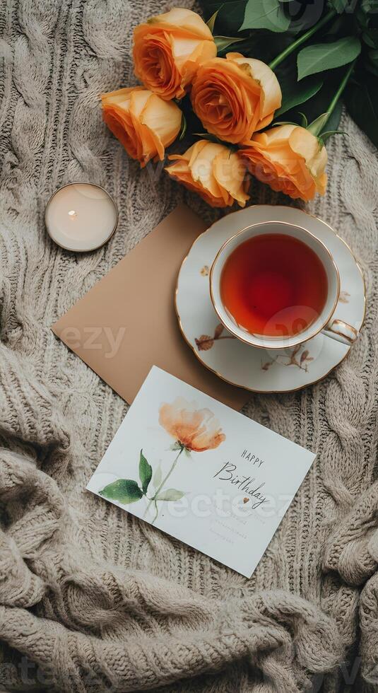 Romantic birthday tea setup with red roses a handmade card and rustic wrapped gift on soft wool blanket photo
