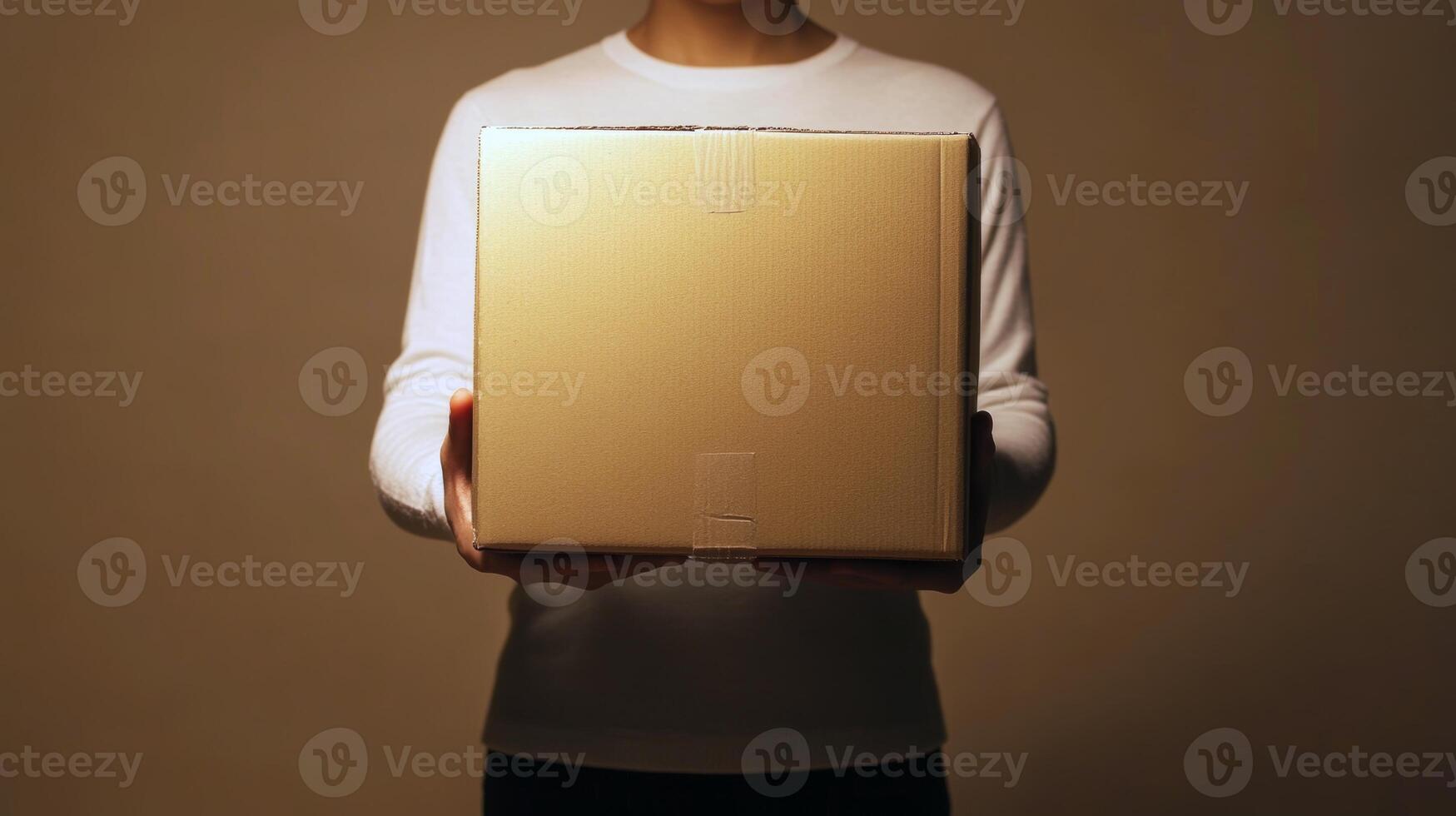 Young adult holding box in hands against minimalist background photo