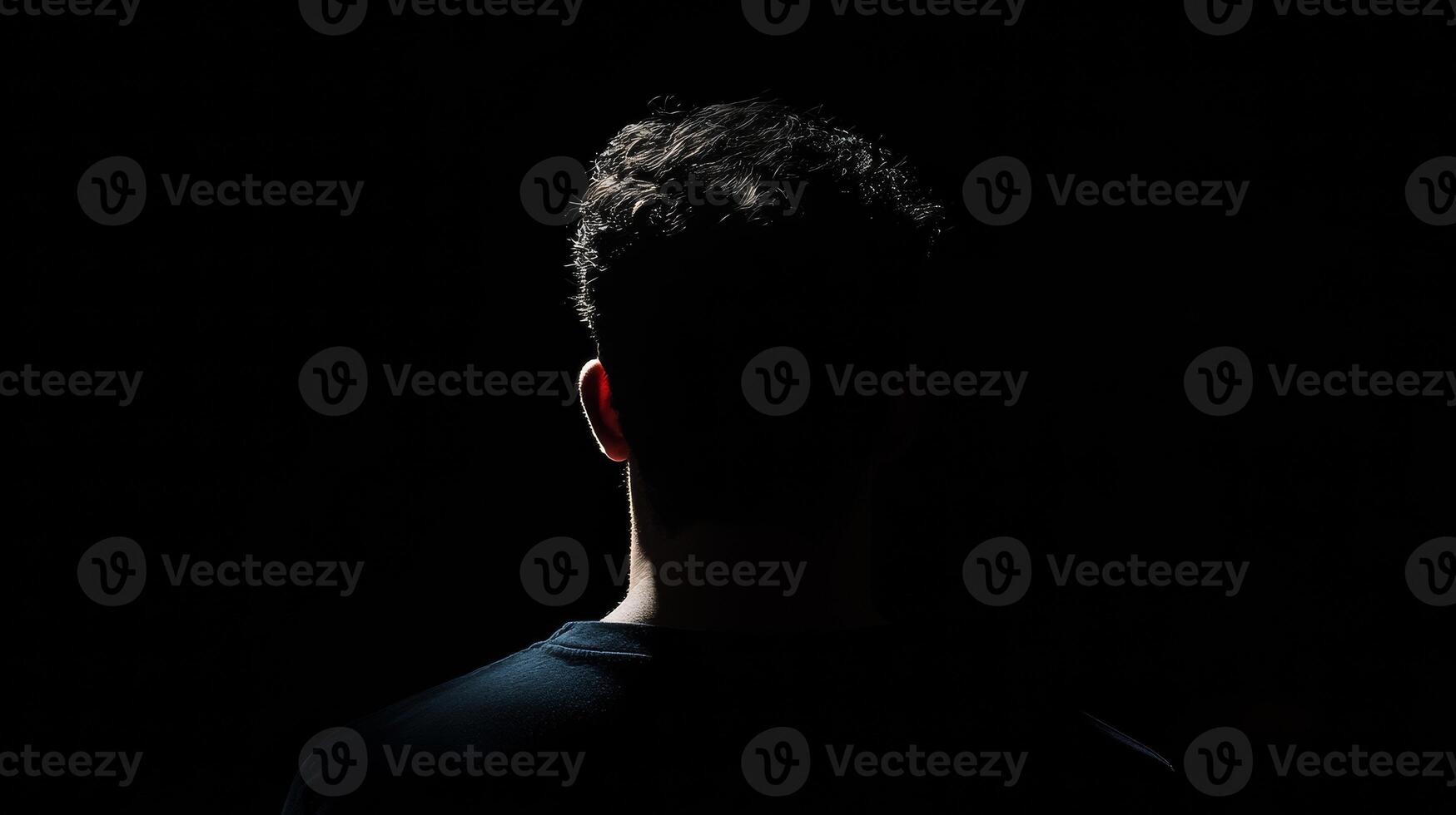 Silhouette of young caucasian male in darkness with curly hair photo