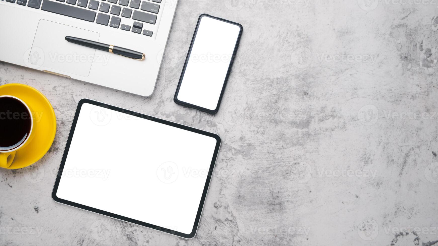 Office desk workplace with blank screen tablet and smart phone, laptop, pen and cup of coffee, Top view flat lay with copy space. photo
