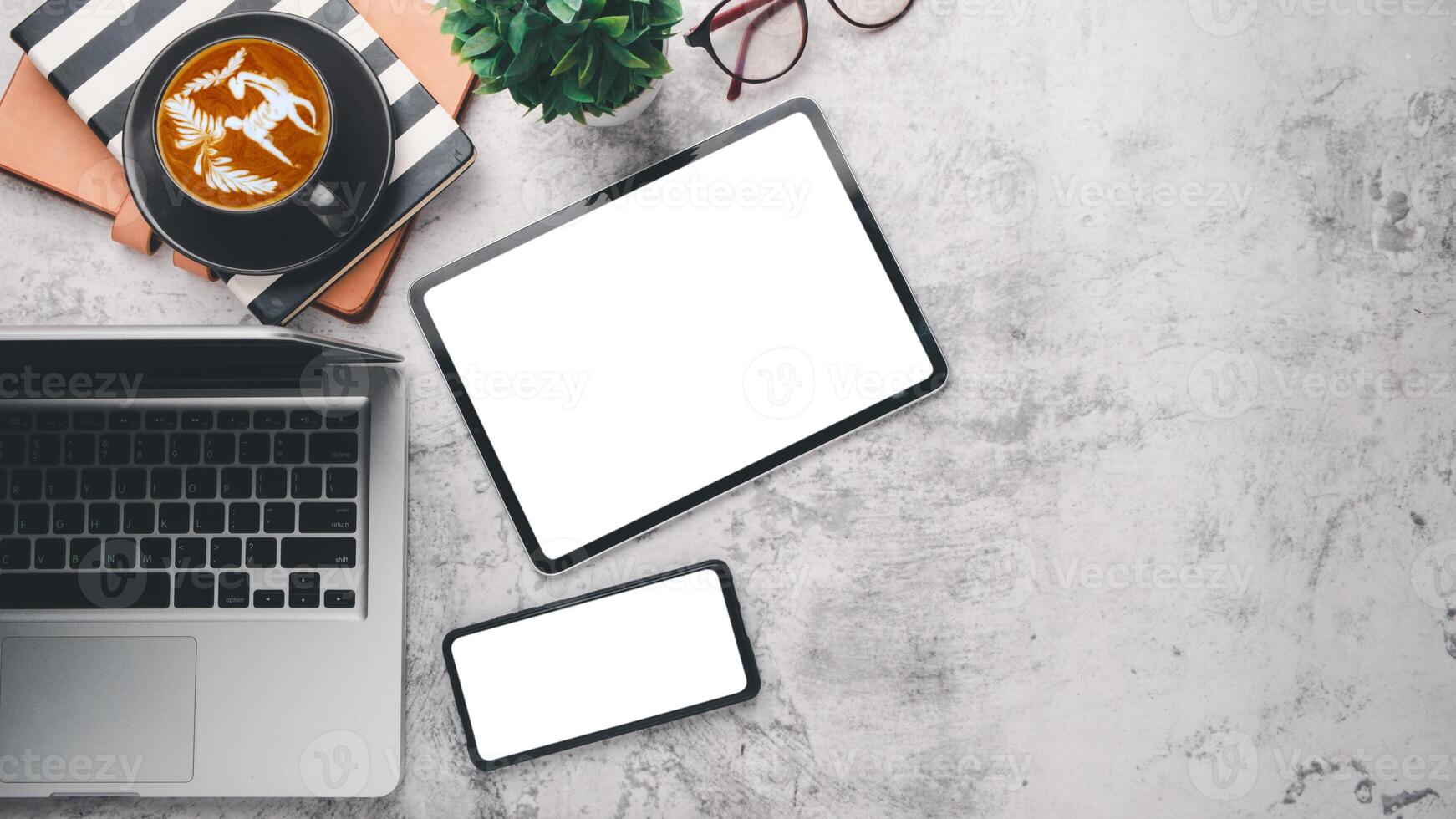 Modern office desk workplace with blank screen digital tablet and smartphone, laptop, eyeglass, notebook and cup of coffee, Top view flat lay with copy space. photo