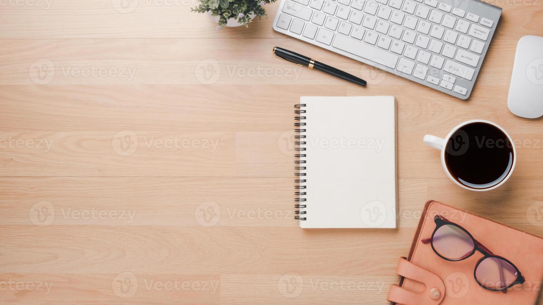 Wooden desk workplace with keyboard computer, mouse, notebook, pen, eyeglass, notebook and cup of coffee, Top view flat lay with copy space. photo