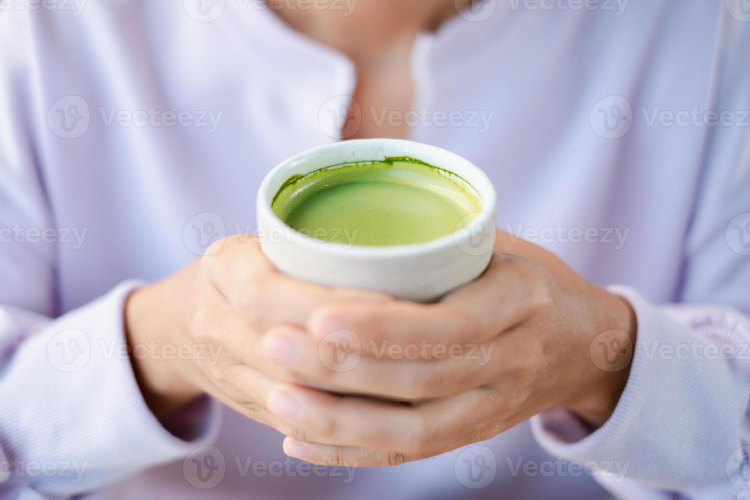 A person holding a cup of vibrant matcha green tea, showcasing warmth and relaxation in a serene environment. photo