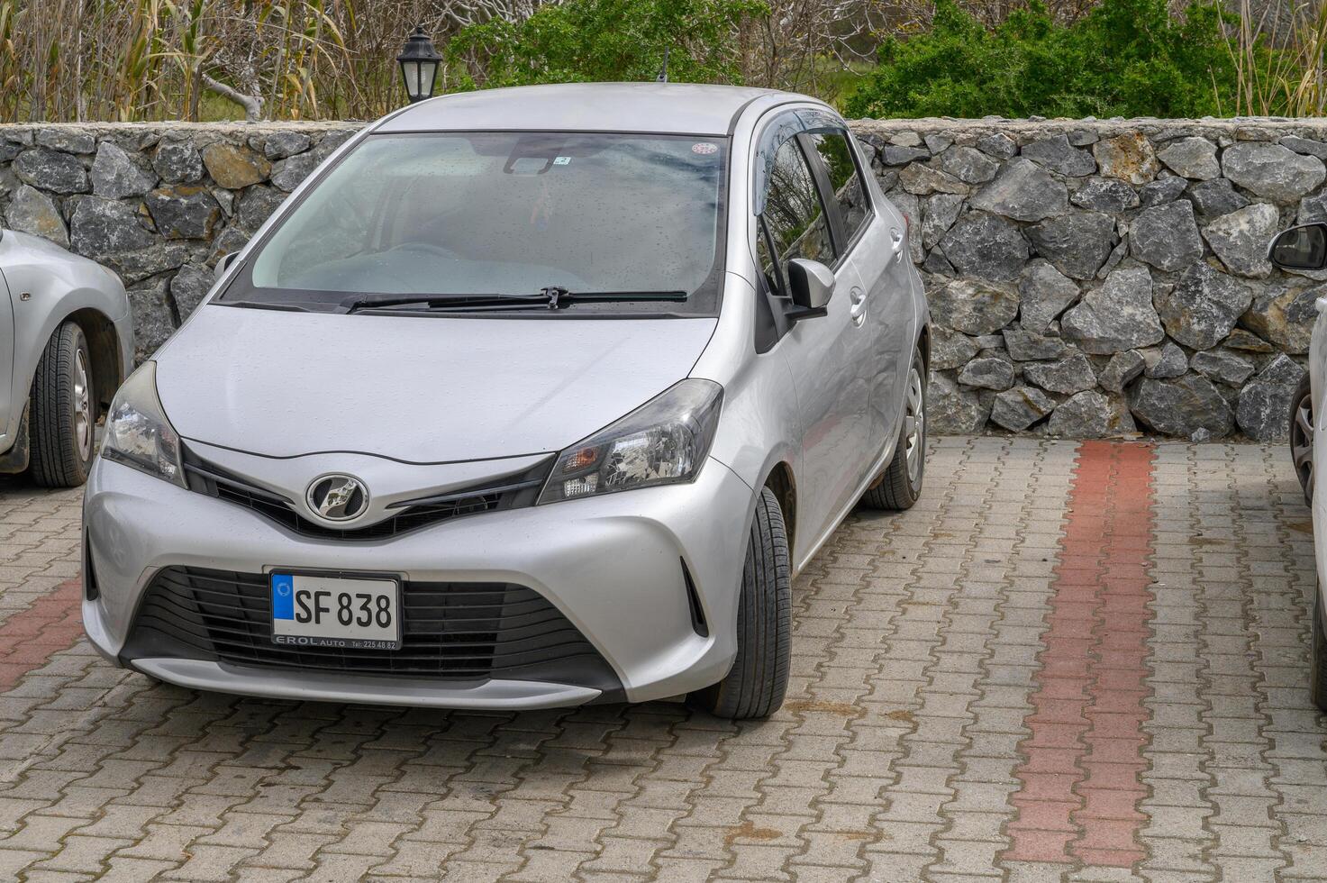 Gaziveren Cyprus -28.02.2025 Silver compact car parked beside stone wall on a cloudy day in a quiet area photo