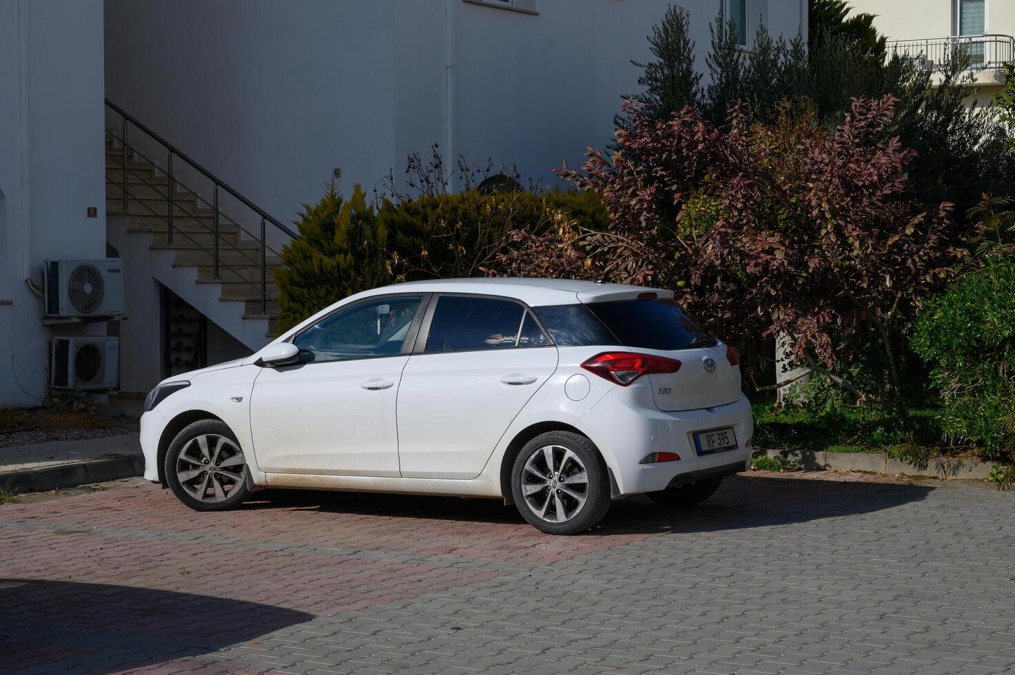 Gaziveren Cyprus -01.03.2025 Parked compact car beside a modern building with vibrant greenery on a sunny day photo