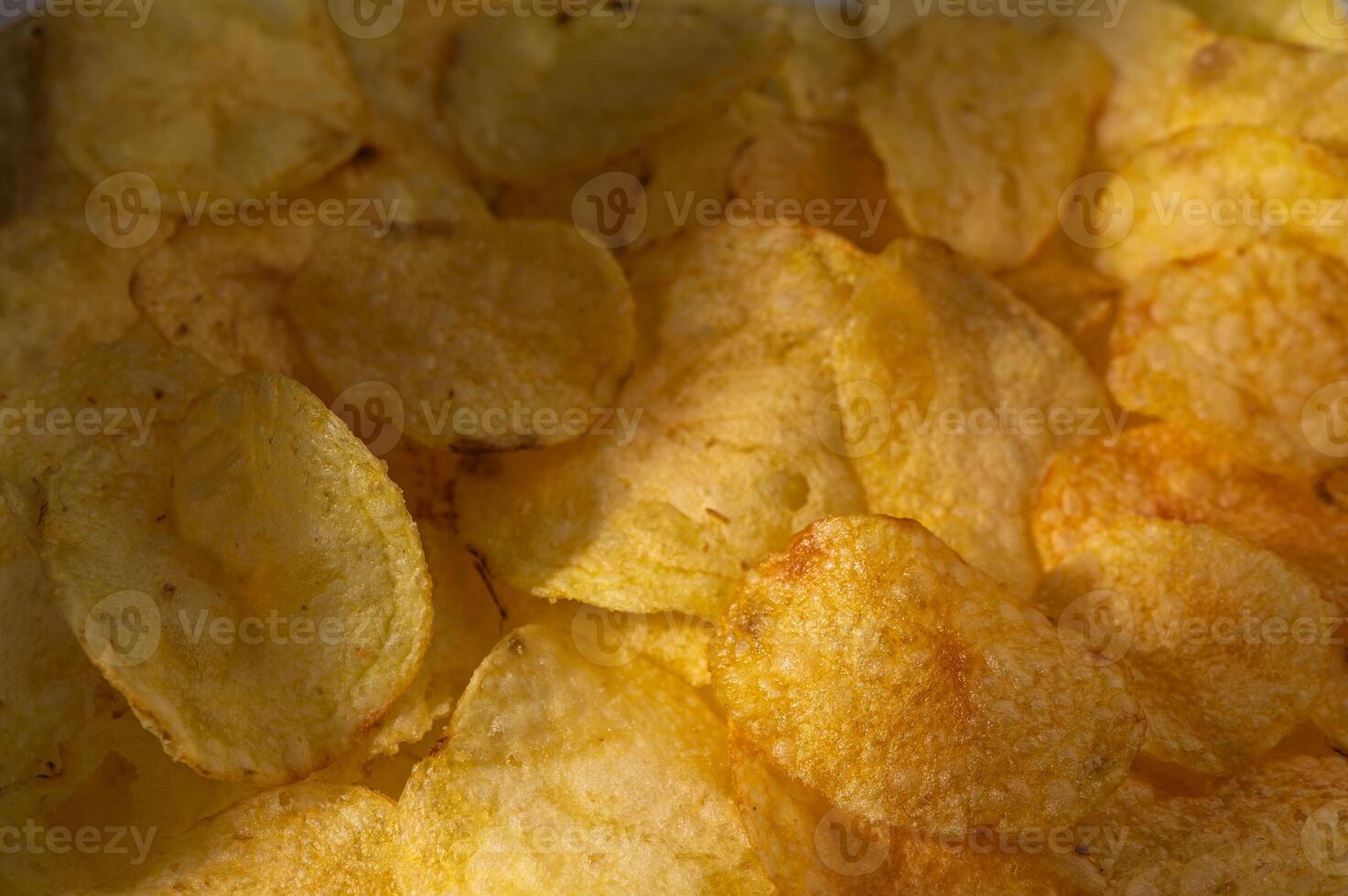 Crunchy potato chips gleaming under warm lights in a cozy snack setting photo