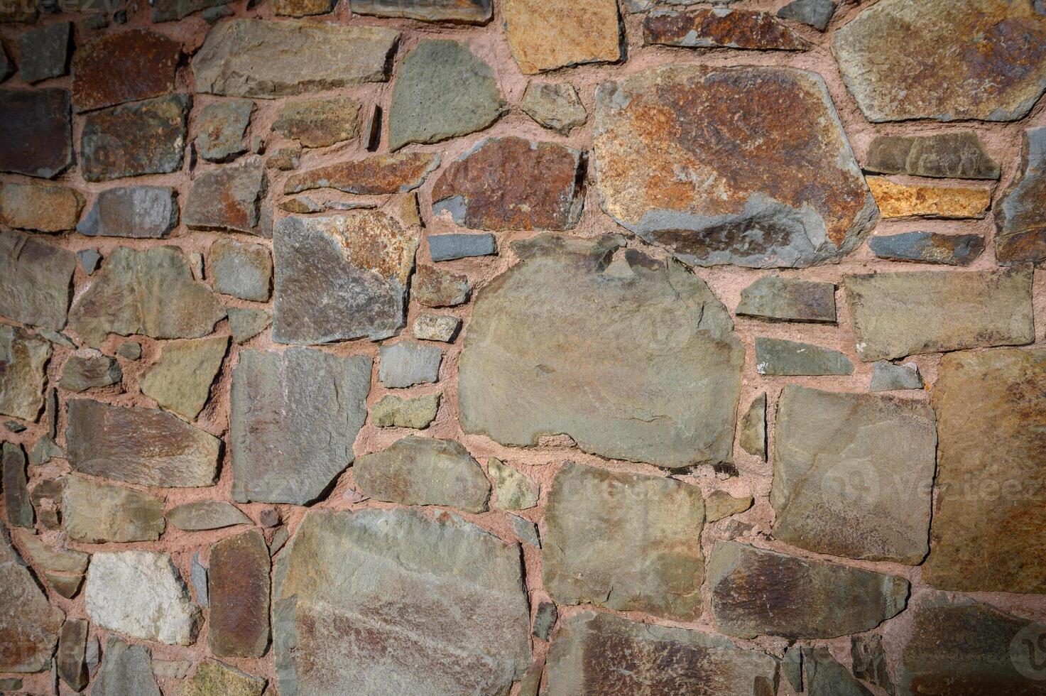 Mosaic of earthy tones highlights a rustic stone wall in the heart of an old village photo