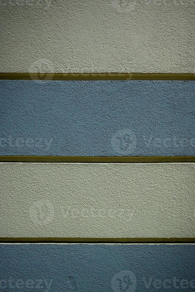 Textured wall with alternating bands of color in a modern architectural setting during daylight photo