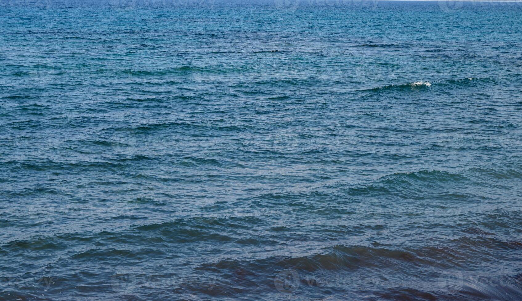 Calm blue waters gently ripple under the soft light of the early afternoon sun photo