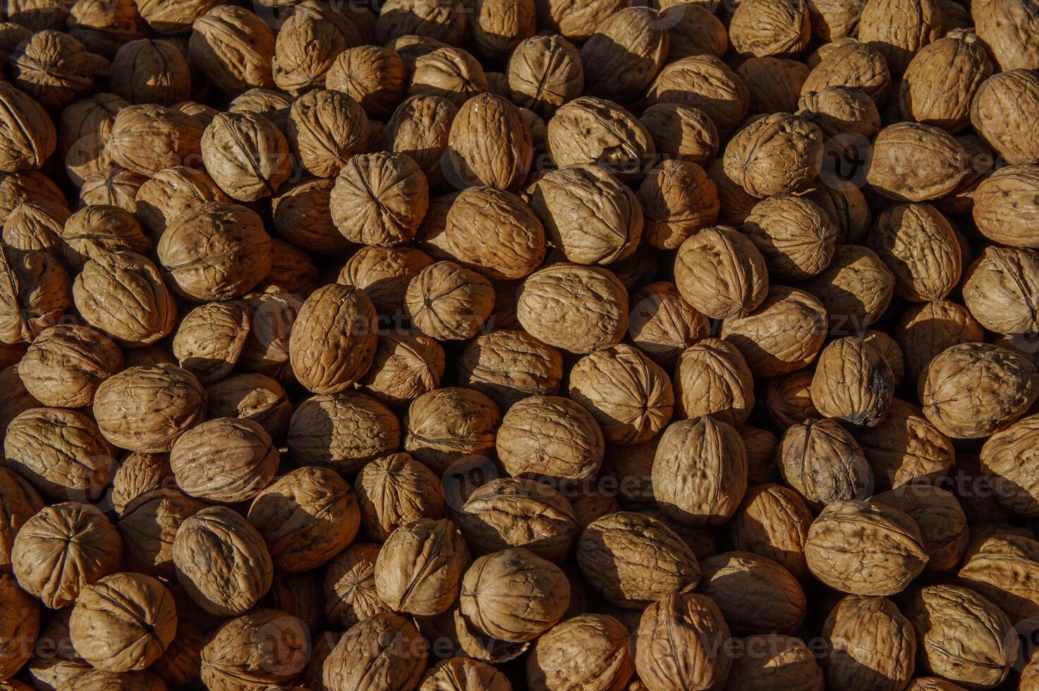 Shelled walnuts spread across a rustic wooden surface under warm sunlight in a vibrant market setting photo