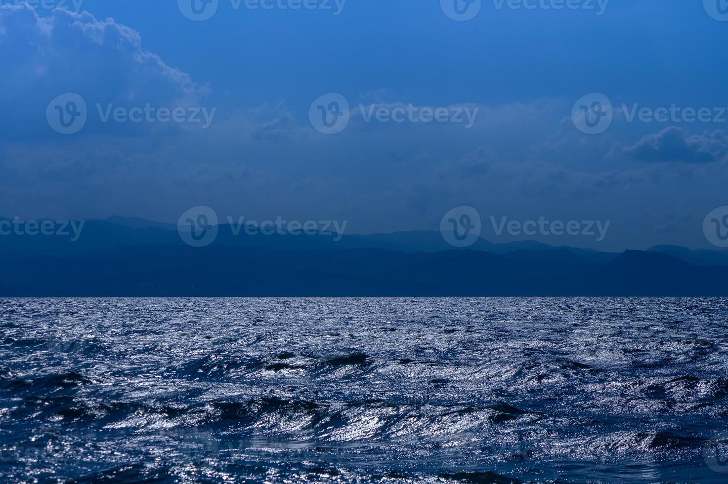 Glistening waves at twilight reflect the colors of a serene evening over the vast ocean horizon photo