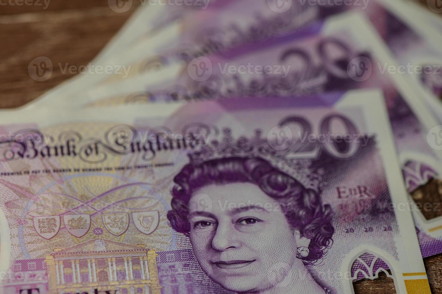 Currency showcasing the intricate designs of UK twenty-pound notes on a wooden surface photo