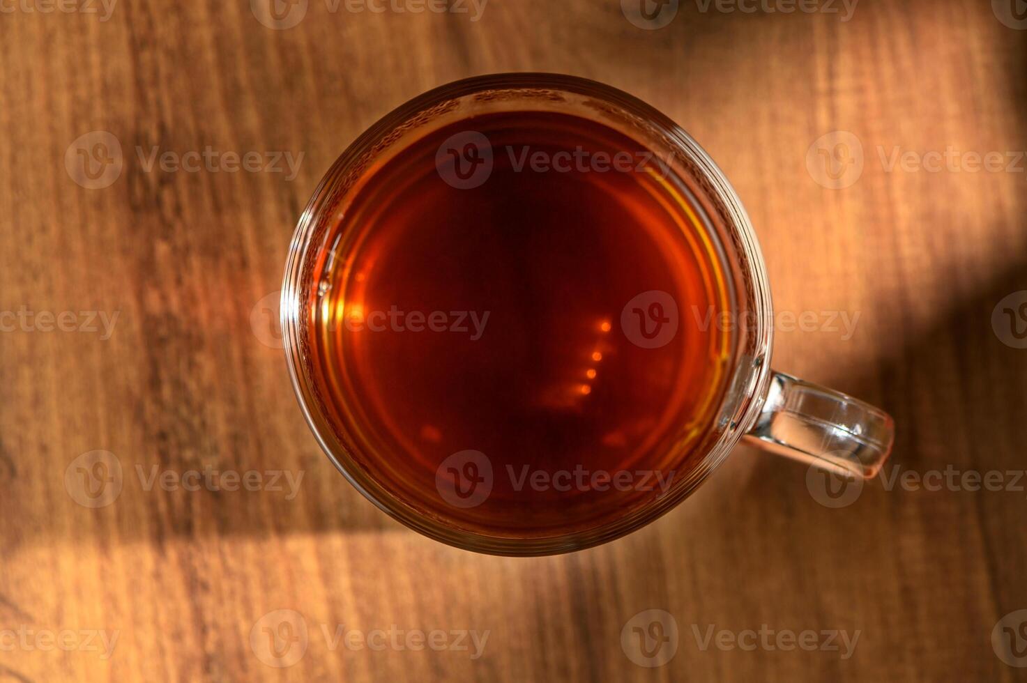 Warm brew in a glass mug resting on a wooden table illuminated by soft afternoon light photo