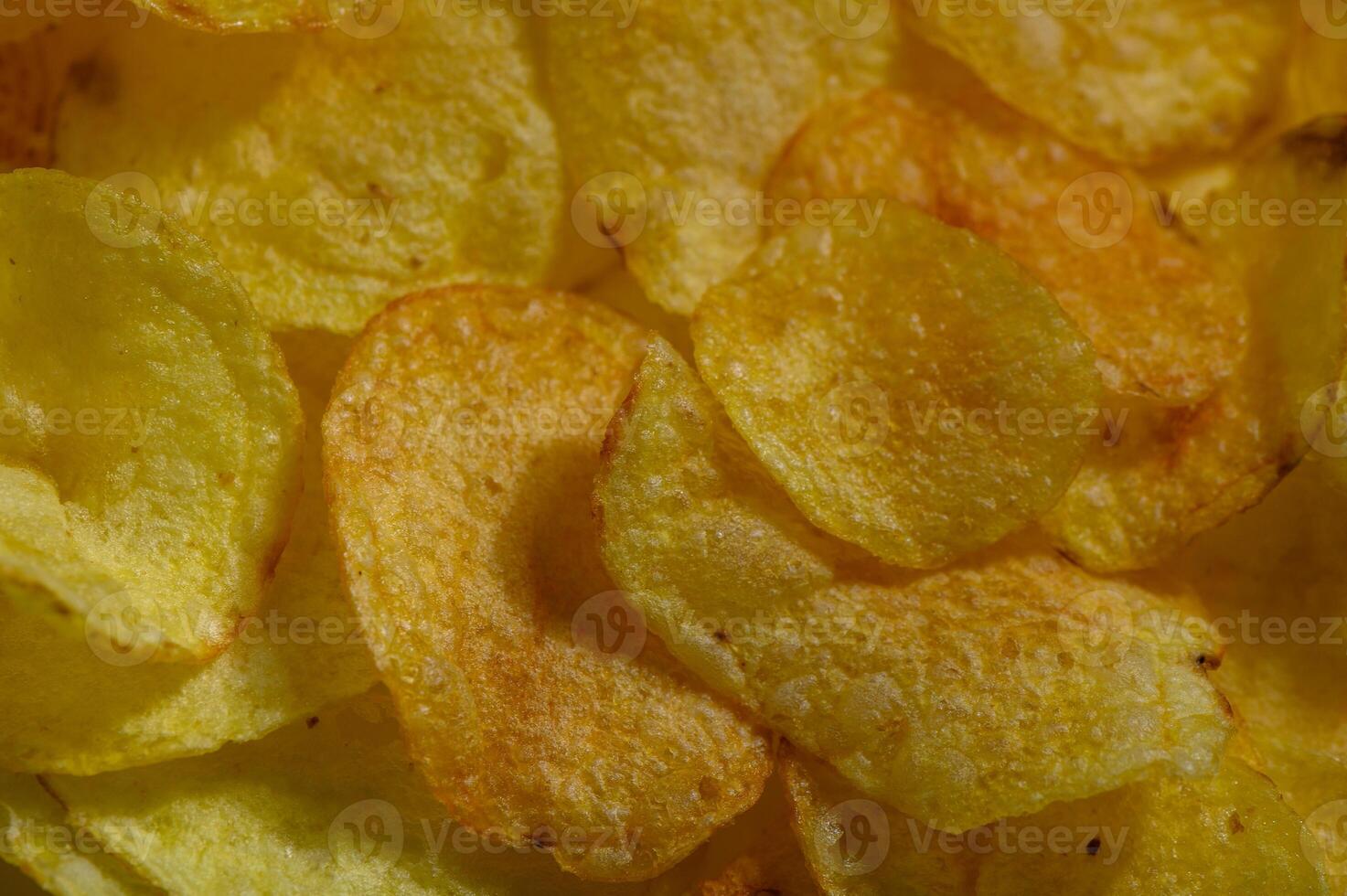 Crispy golden potato chips scattered in an inviting bowl during an afternoon snack session photo