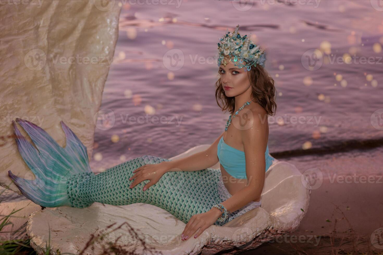 Beautiful Girl mermaid sitting near water at dusk photo
