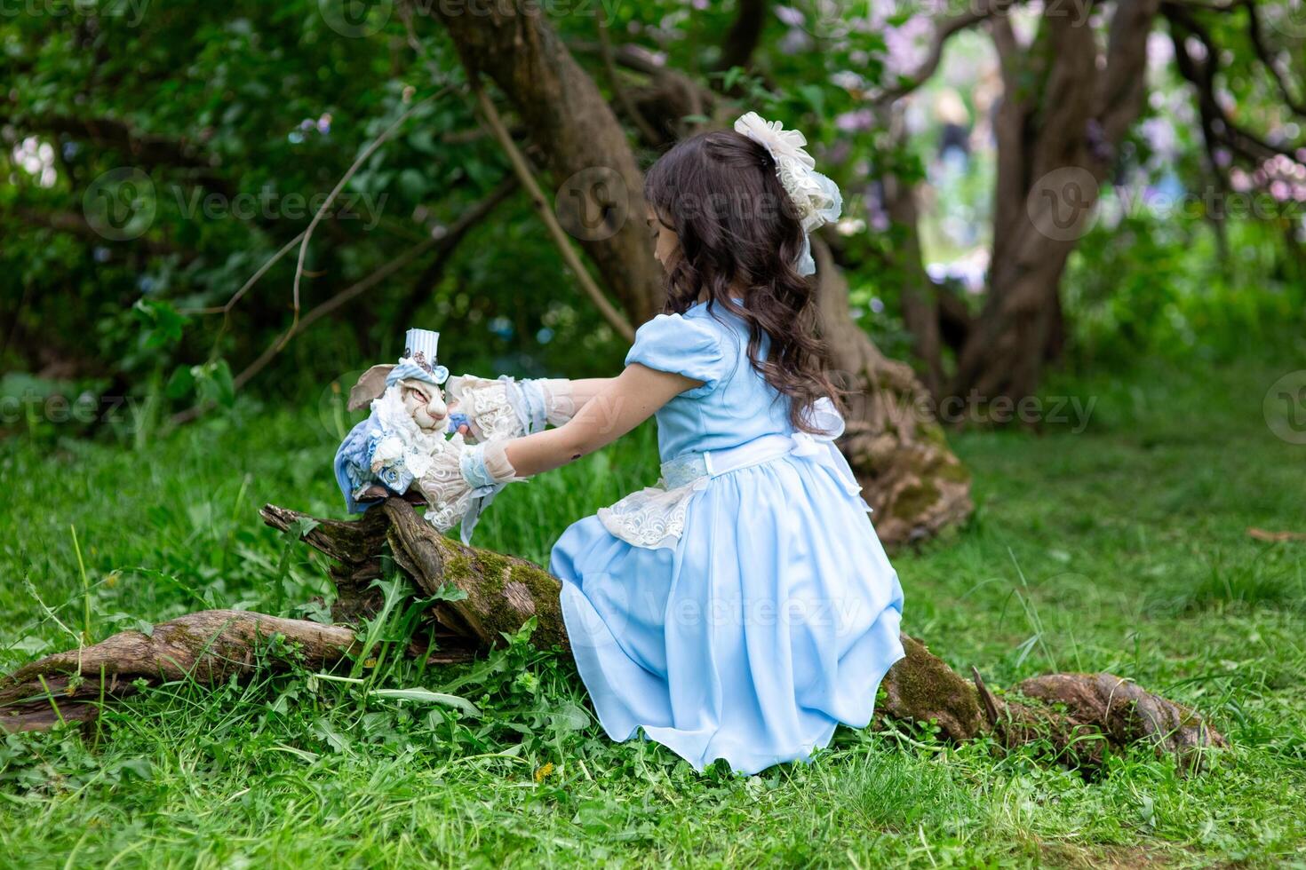 Young brunette girl in blue dress playing with toys in forest photo
