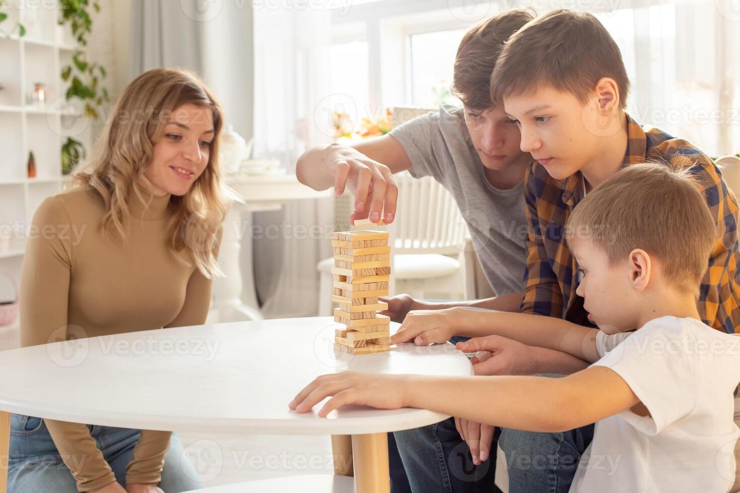 Family , in home enthusiastically play a board game made of wooden rectangular blocks photo