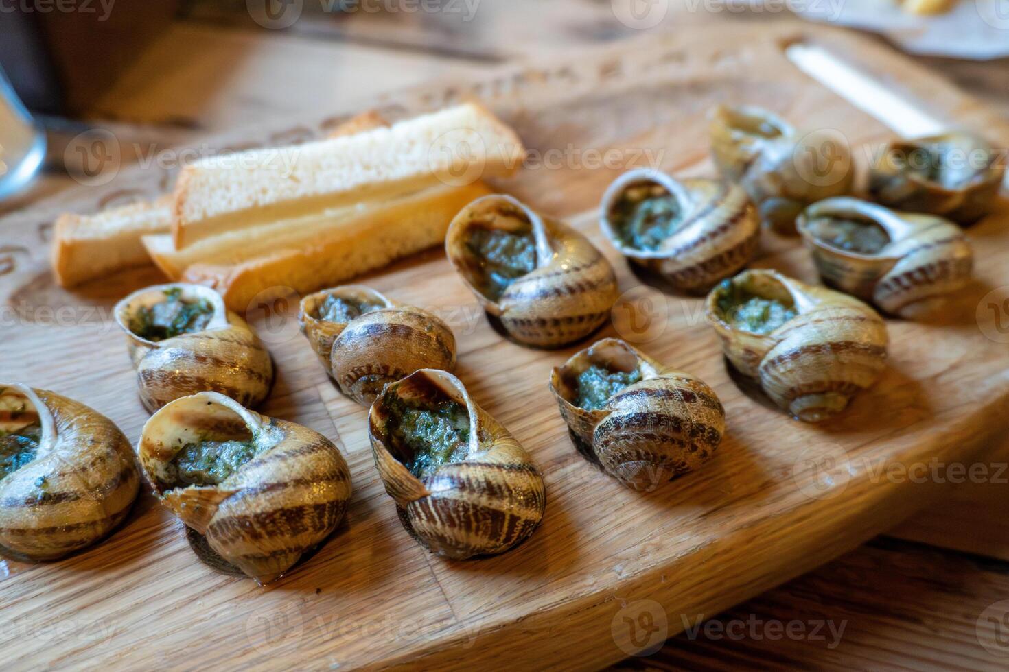 Escargot platter with herb butter and toasted bread on wooden board photo