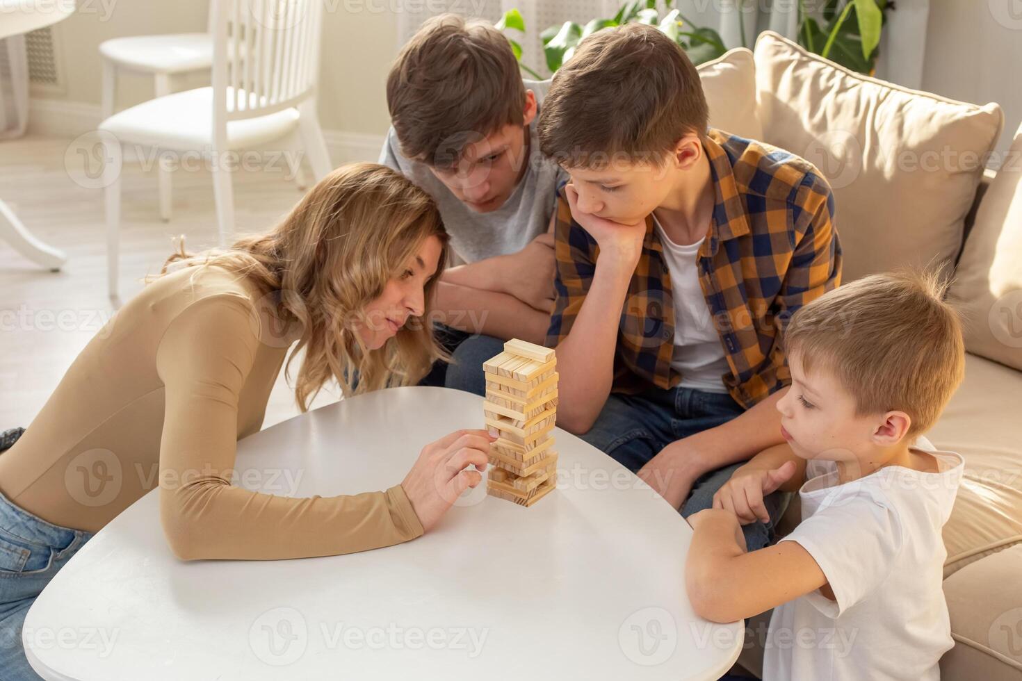 Family , in room play a board game made of wooden rectangular blocks photo
