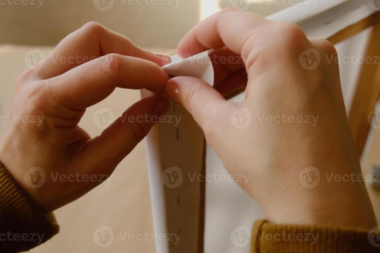 Framer hands bend edges of canvas. Stretching blank canvas on stretcher frame. Close-up. photo