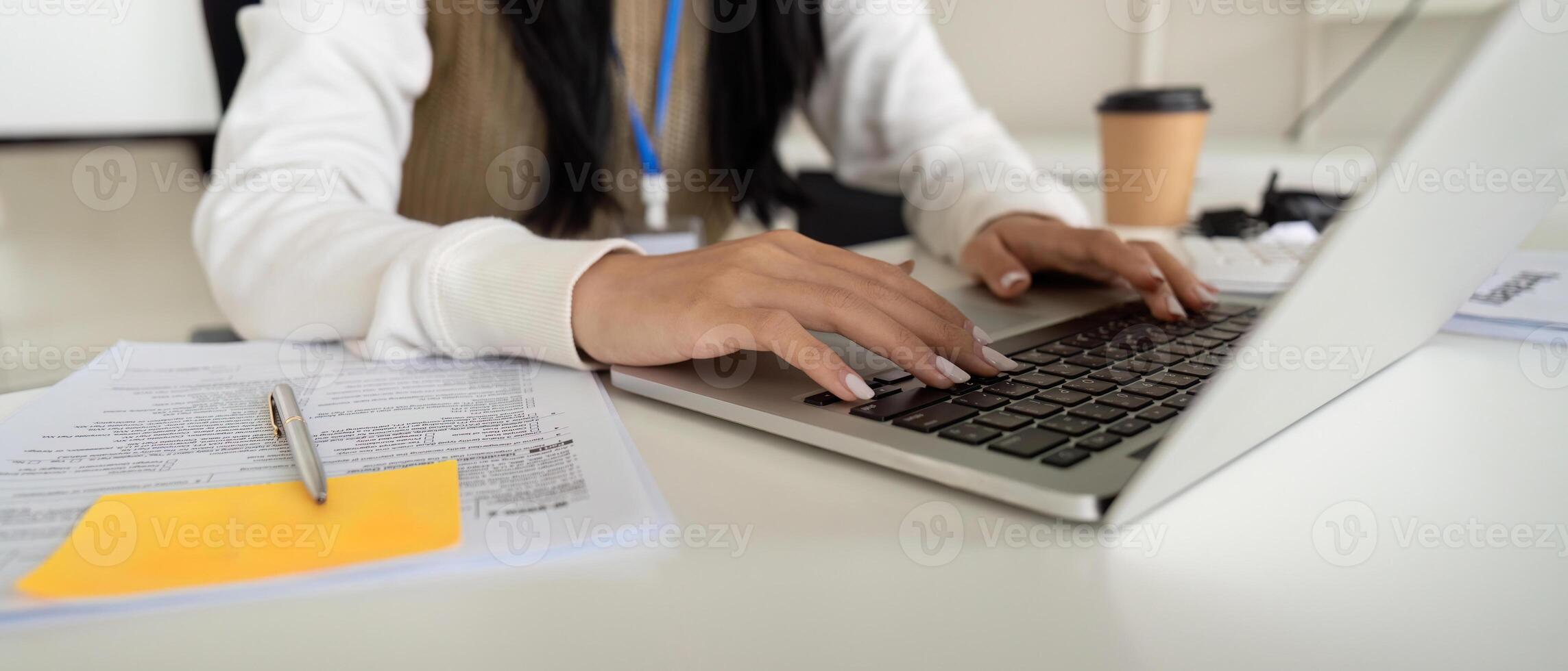 Financial professional typing on a laptop while reviewing tax documents and calculations. photo