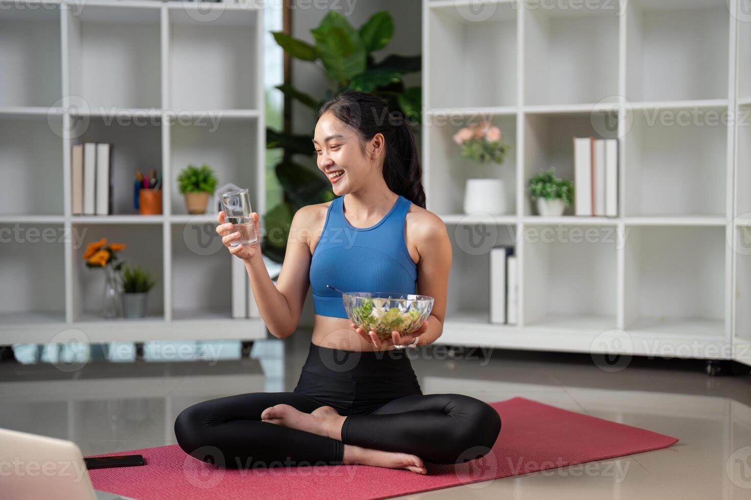 Health-focused woman drinking water while enjoying a salad, promoting hydration and nutrition. photo