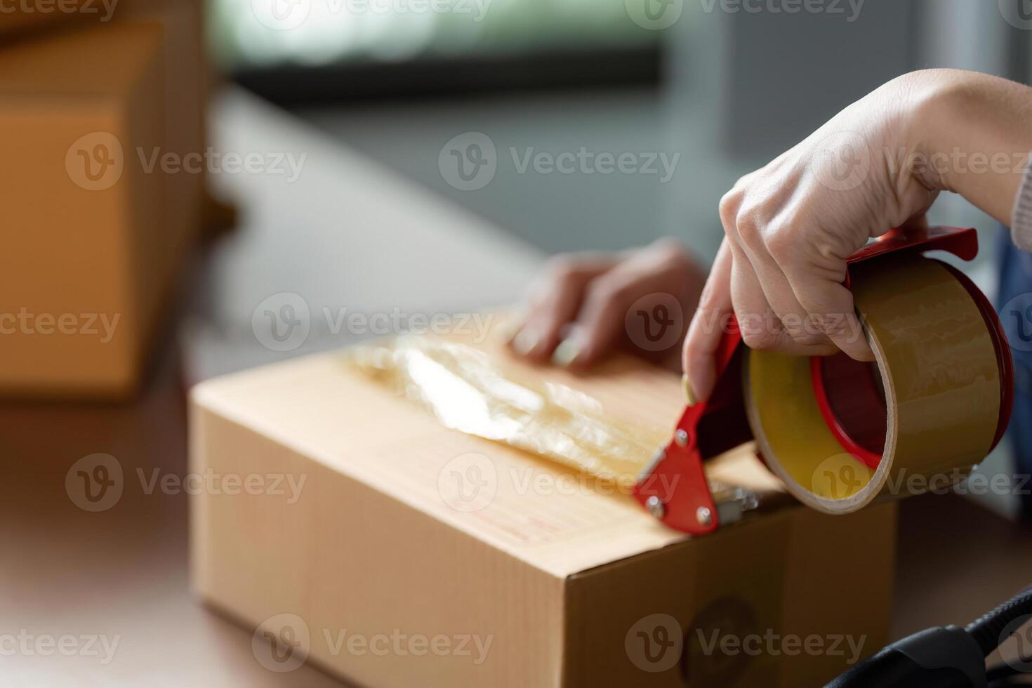 Person sealing a package with tape for online shipping photo