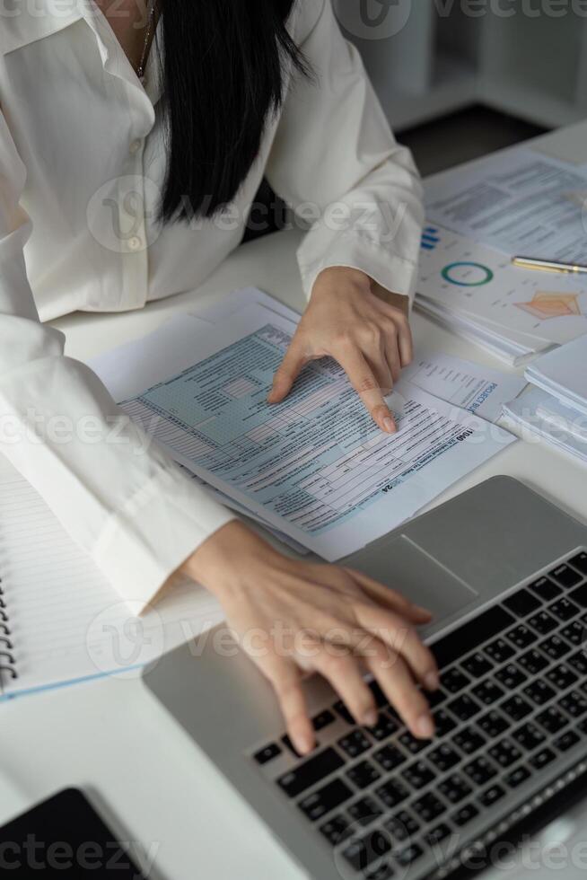Accountant analyzing financial data on a laptop while reviewing tax documents. photo