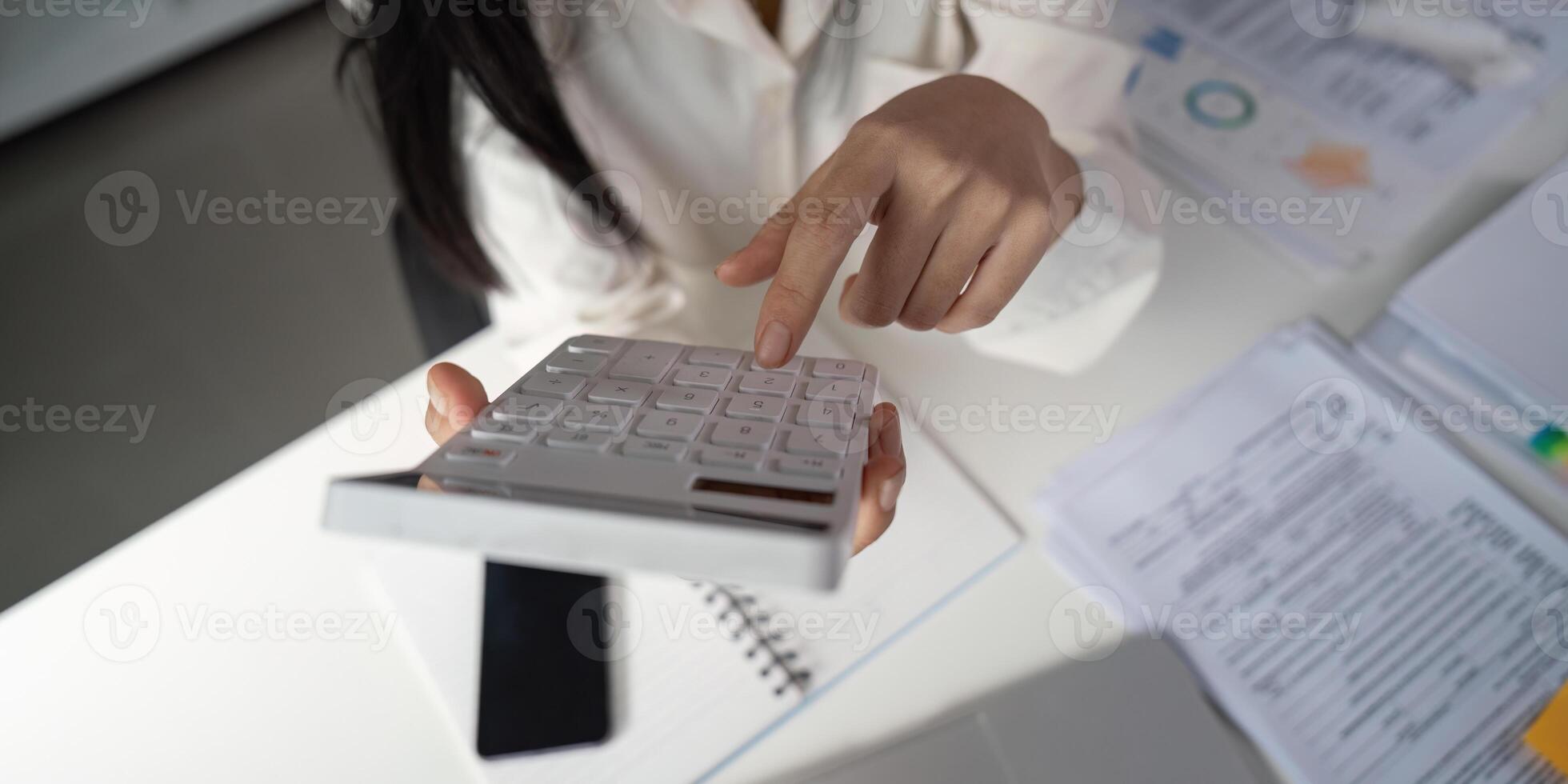 Tax preparation professional typing on a laptop while holding organized documents. photo