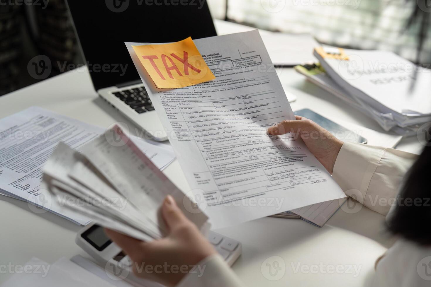 Person analyzing tax paperwork and using a calculator for financial calculations. photo