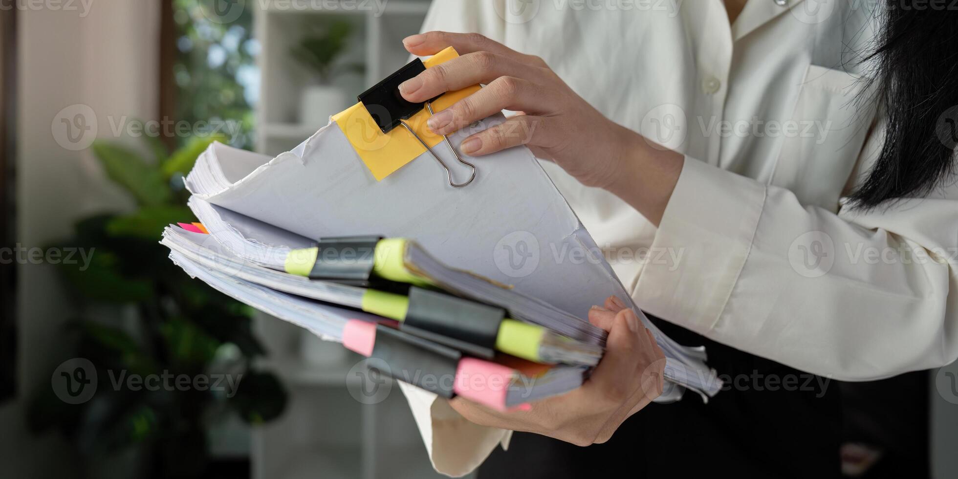 Individual reviewing tax documents with a magnifying glass while seated at a desk. photo