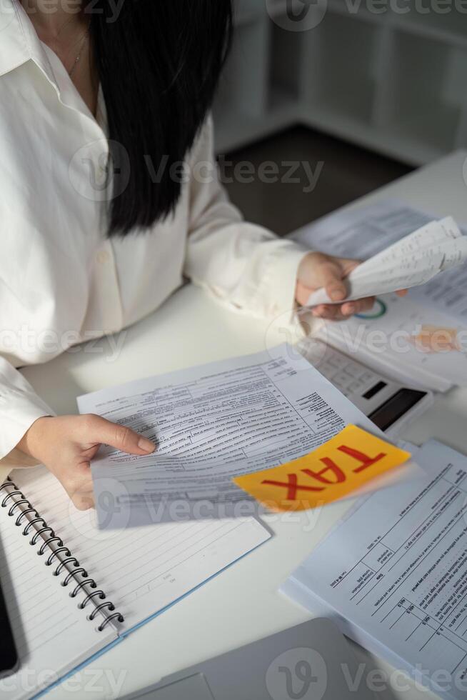 Individual typing on a laptop while managing tax documents on a desk. photo