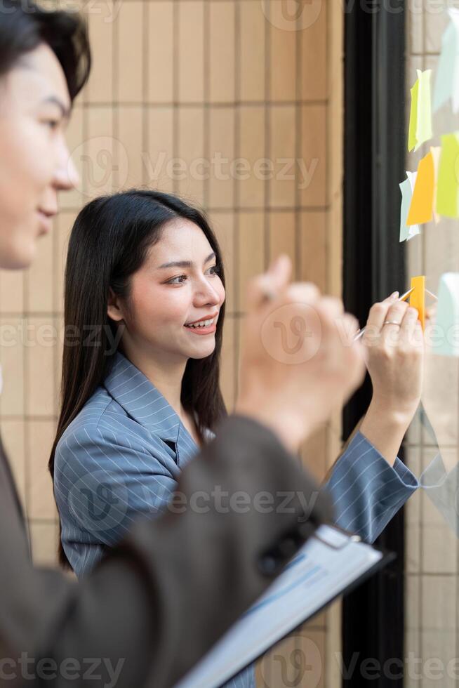 Team members collaborating on project ideas with sticky notes on a glass board. photo