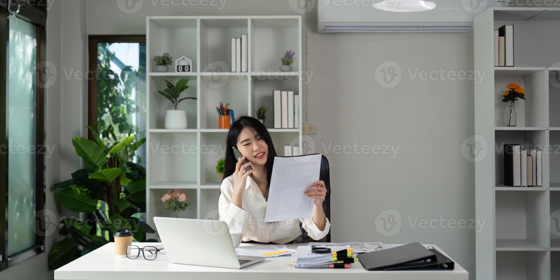 Accountant on a call while holding tax documents and smiling at the camera. photo