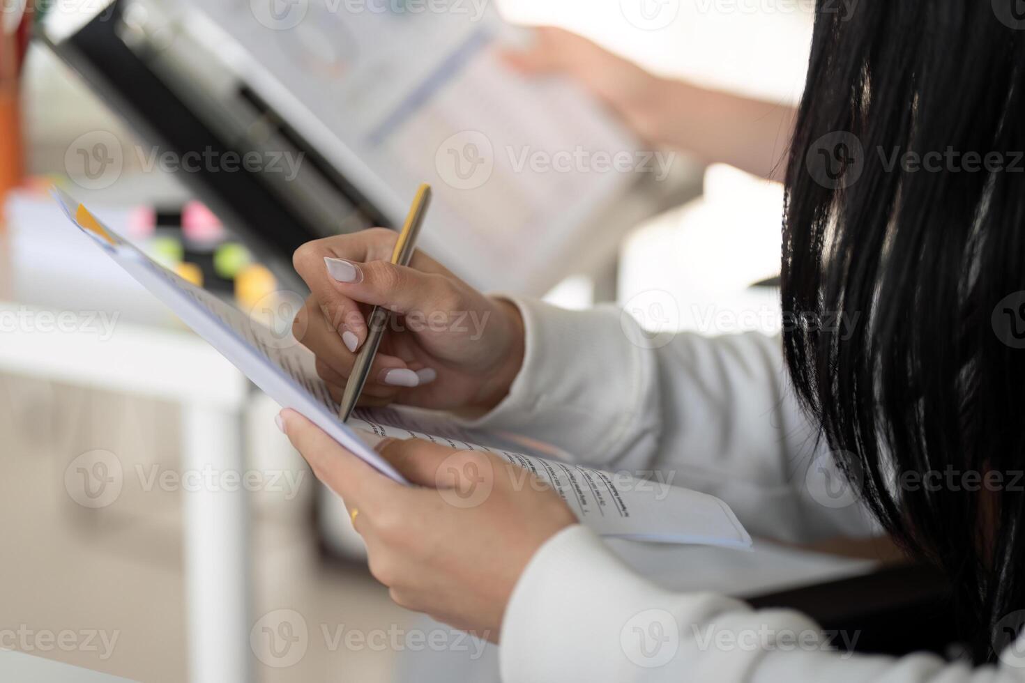 Close-up of hands reviewing financial documents and making notes photo