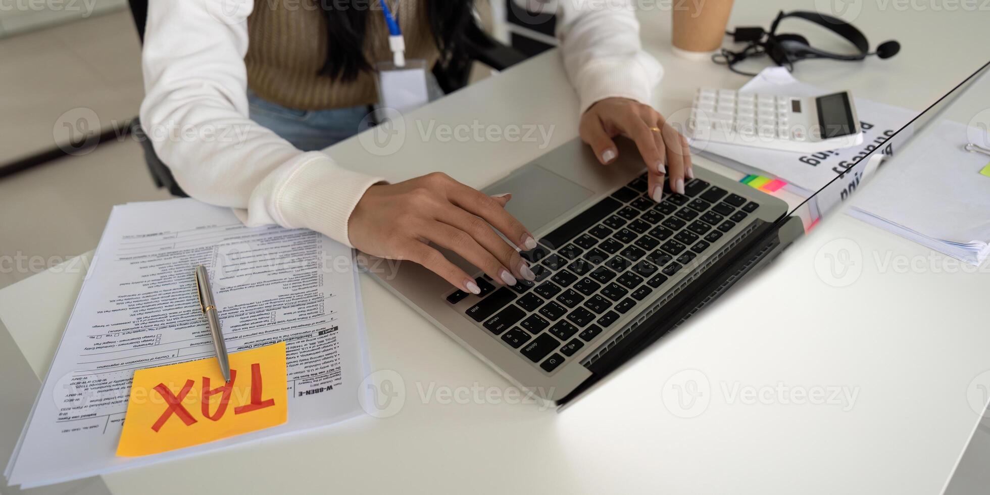 Focused young professional working on tax documents and calculations at a desk. photo