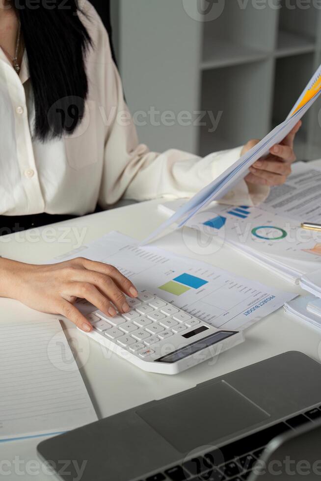 Accountant using a calculator and reviewing financial reports in a modern workspace. photo