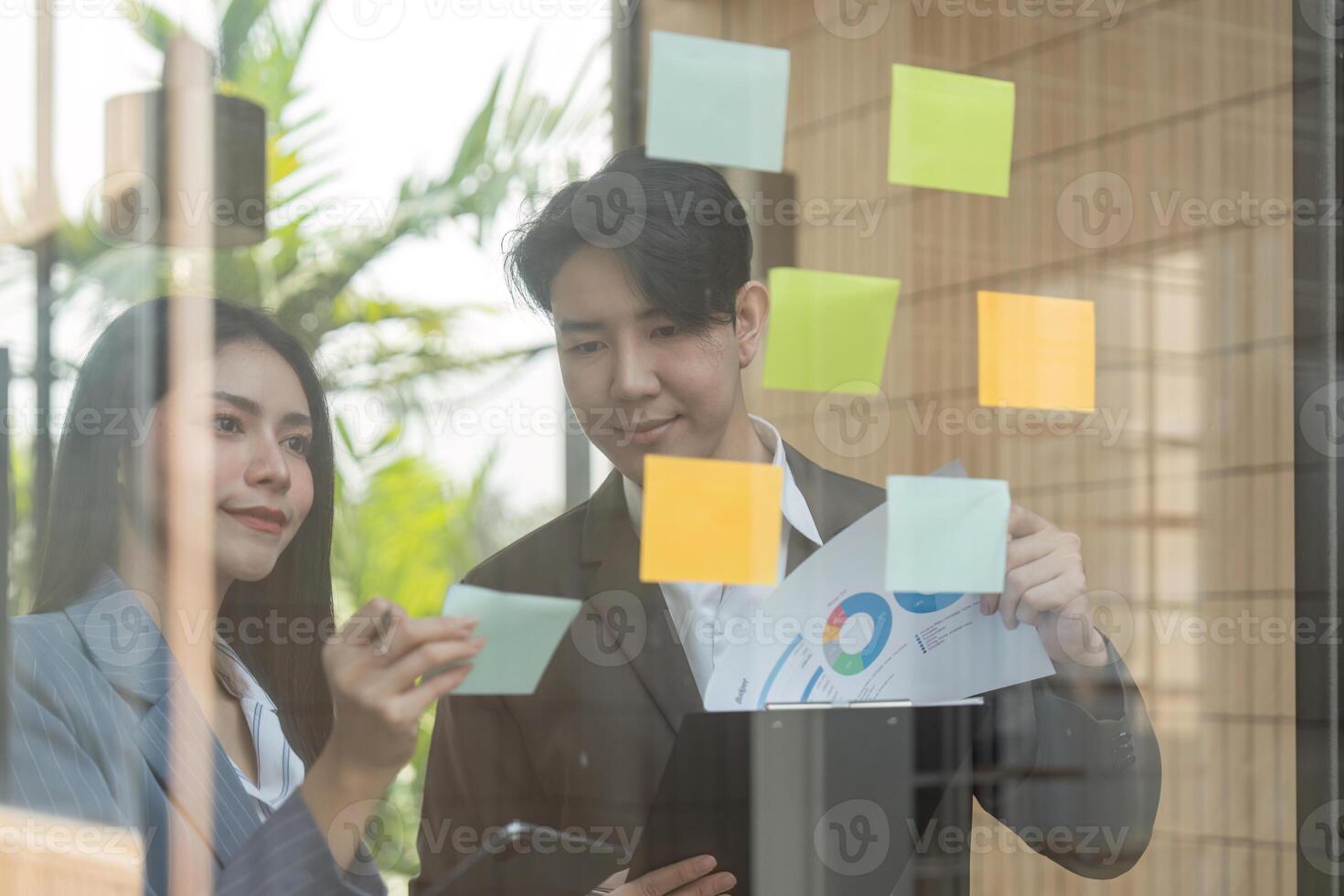 Business professionals reviewing project details on a tablet in a vibrant office setting. photo
