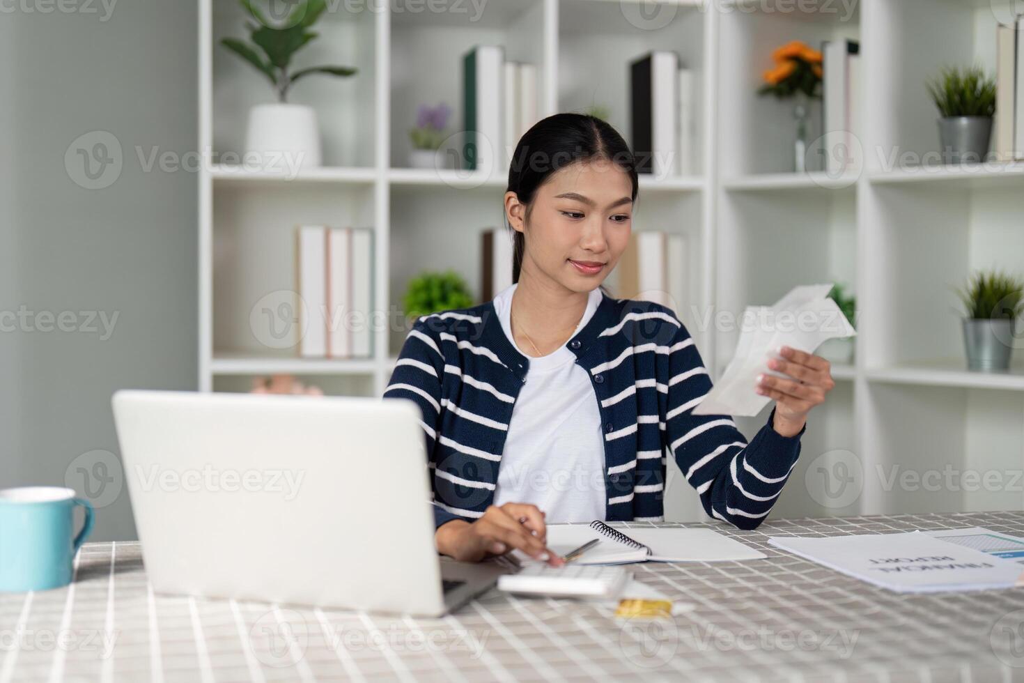 Woman using credit card while managing finances on laptop, focusing on budgeting and expenses. photo