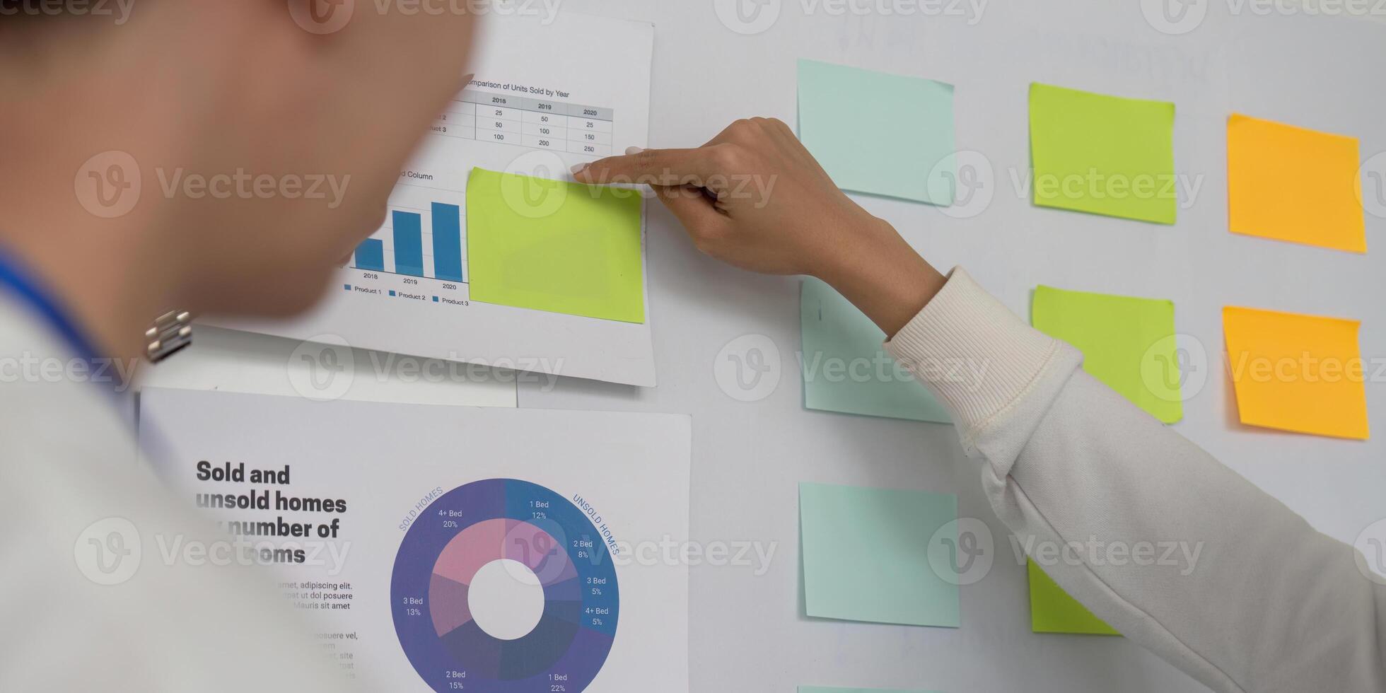Colleagues discussing financial data insights and strategies on a whiteboard. photo