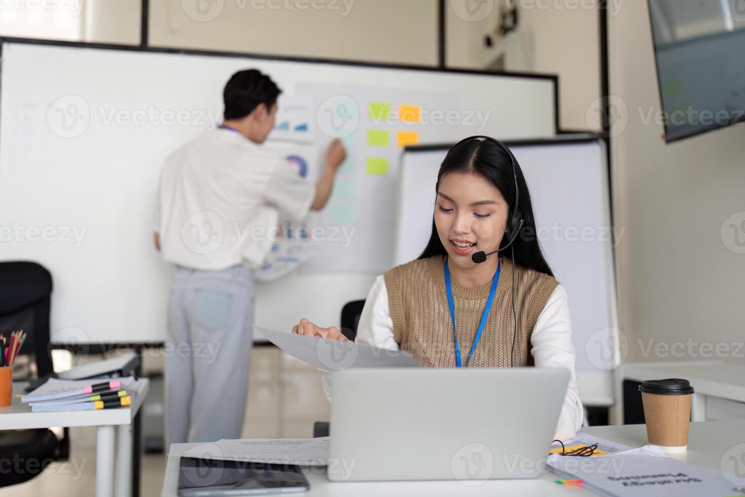 Finance analyst working on a laptop while discussing tax deductions with a colleague in a modern office. photo