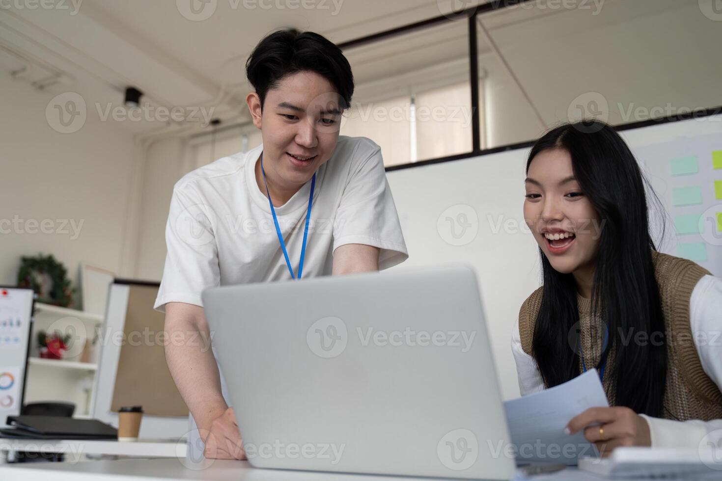 Young professionals collaborating on financial analysis using a laptop in a modern office setting. photo
