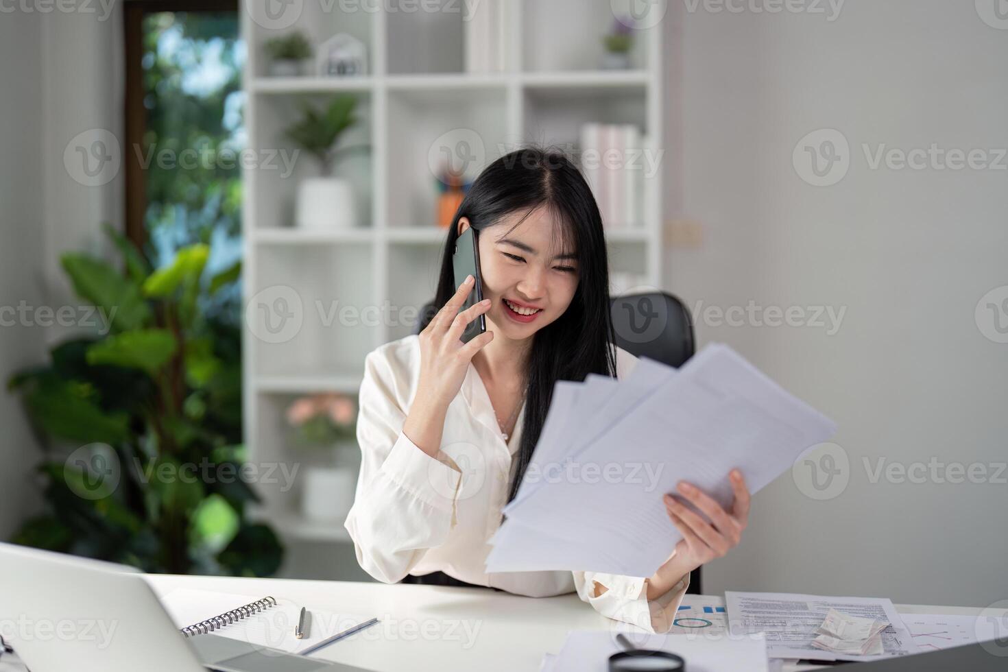 Overhead view of a young woman preparing tax documents and calculating finances at her desk. photo
