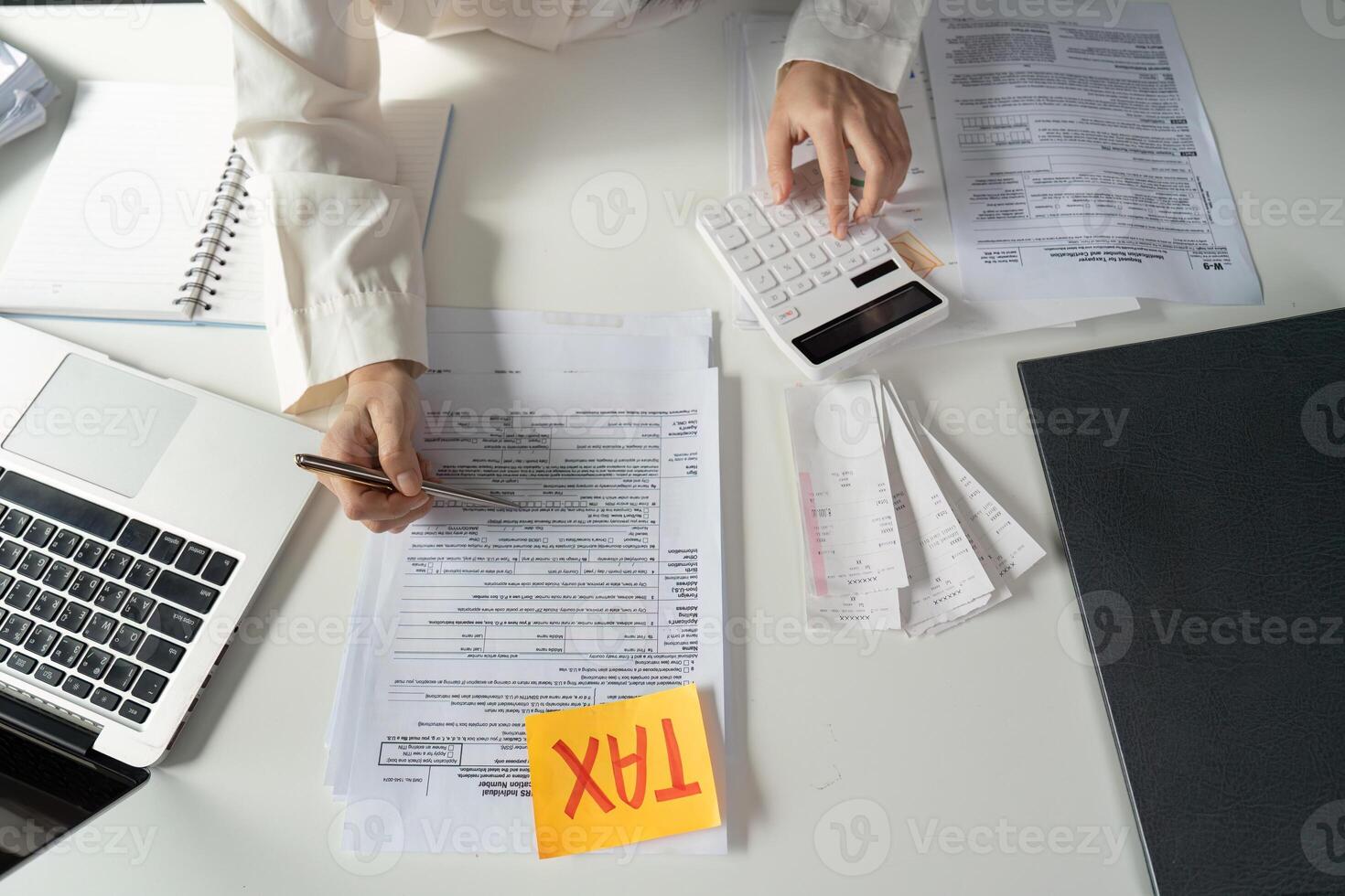 Young woman calculating taxes and preparing financial documents at a desk with a calculator. photo