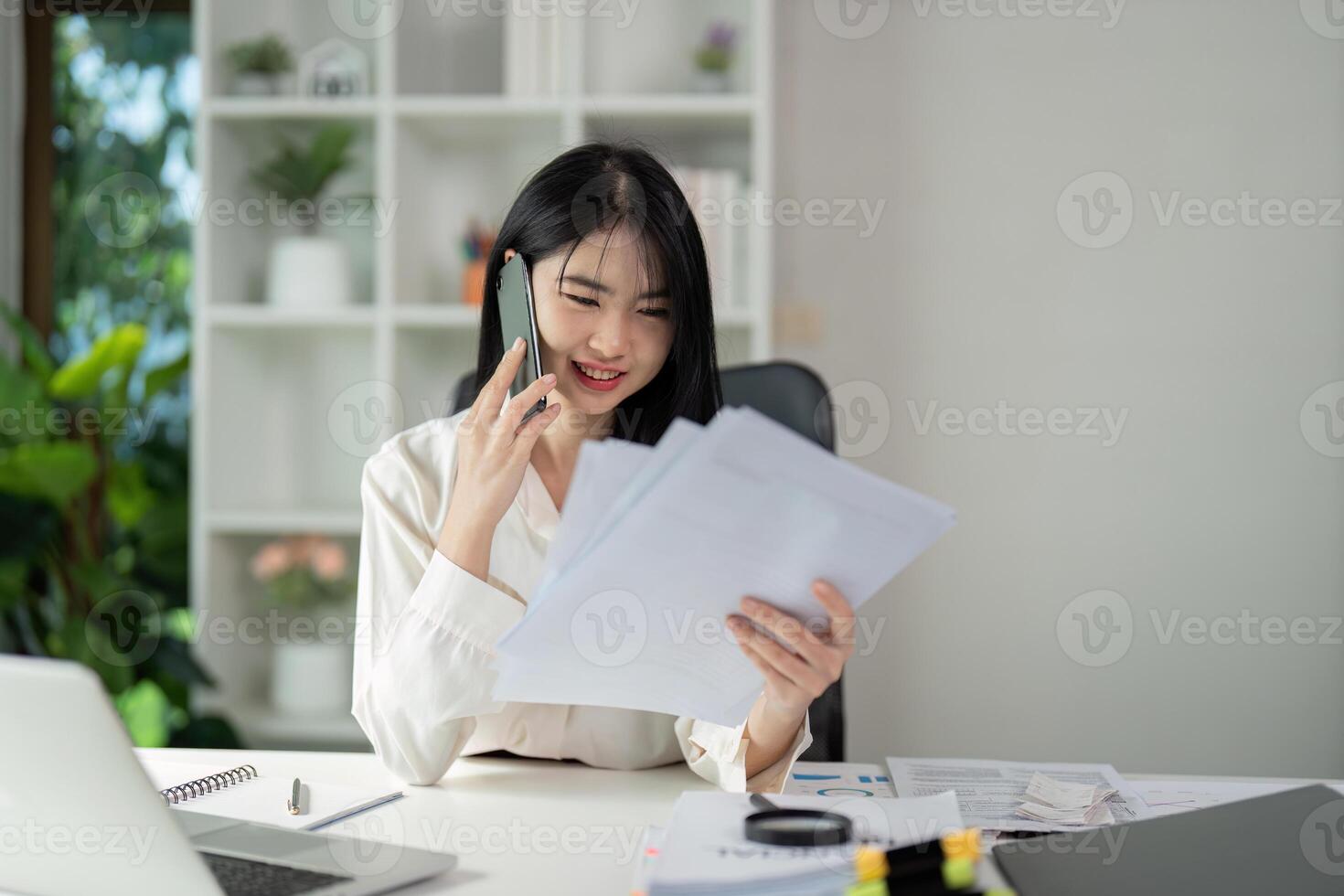 Tax Report Communication. A professional woman engages on a call while reviewing tax documents. photo