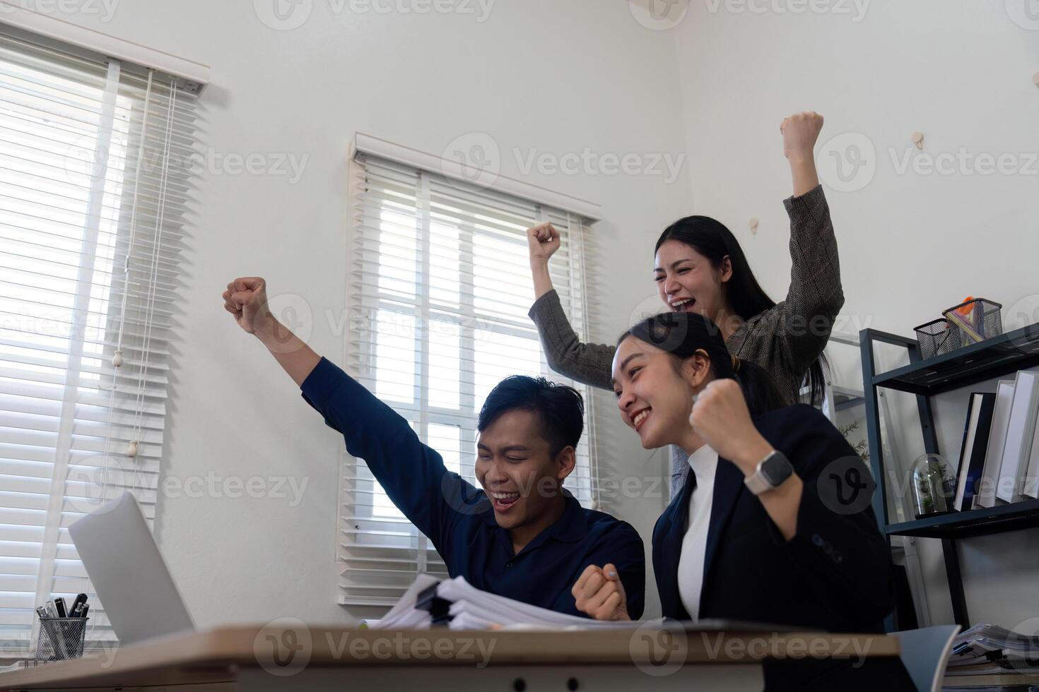 Excited team celebrating success in a modern office, showcasing teamwork and achievement. photo