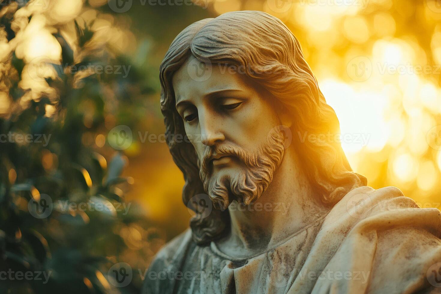 Ancient stone statue of Jesus Christ looking down with golden light in the background photo