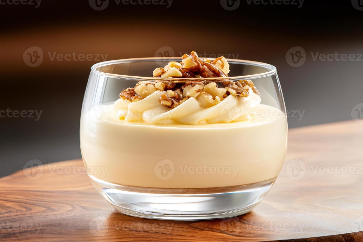 Creamy dessert with walnuts and pecan nuts in a glass bowl on wooden table photo