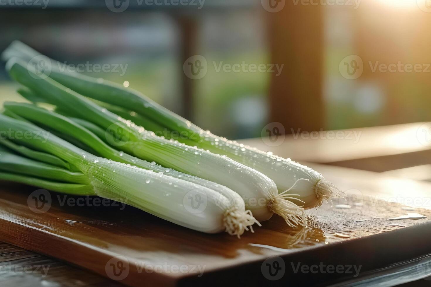 Fresh spring onions with water drops on wooden cutting board photo