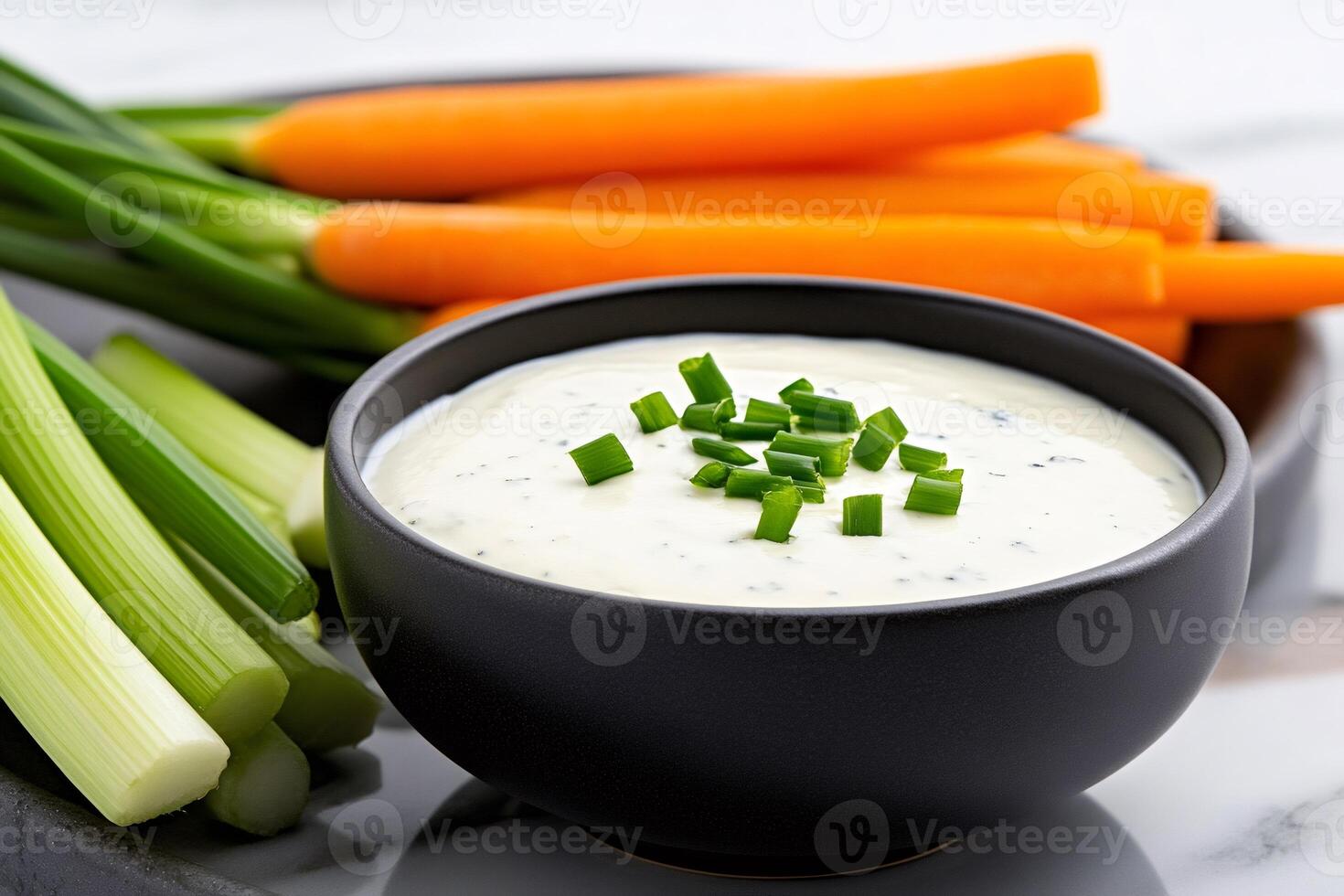 Creamy dip seasoned with chopped chives served with fresh carrots and celery sticks photo